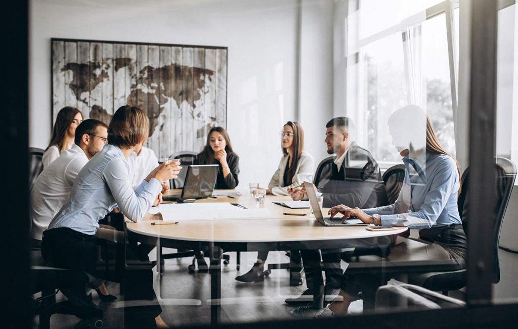 Grupo diverso de personas sentadas al rededor de una mesa, en una reunión